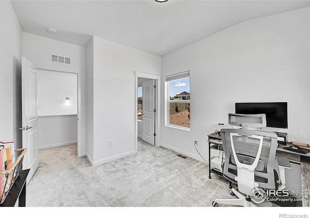 carpeted home office featuring baseboards, vaulted ceiling, and visible vents