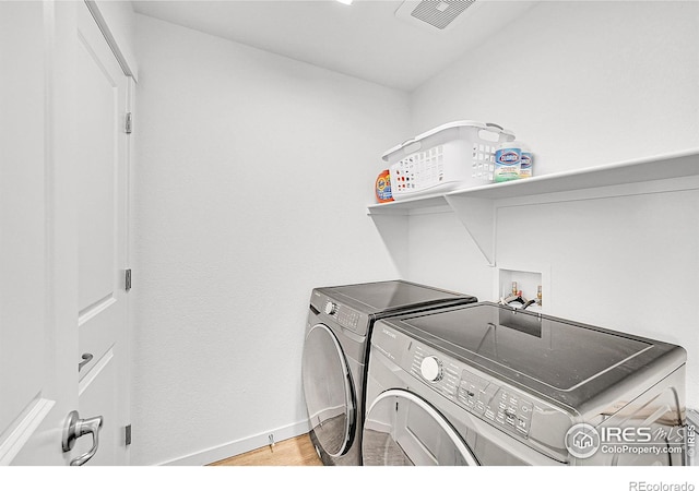 washroom with baseboards, visible vents, light wood-style floors, separate washer and dryer, and laundry area