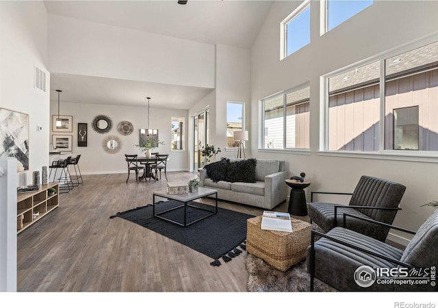 living area featuring baseboards, wood finished floors, visible vents, and high vaulted ceiling