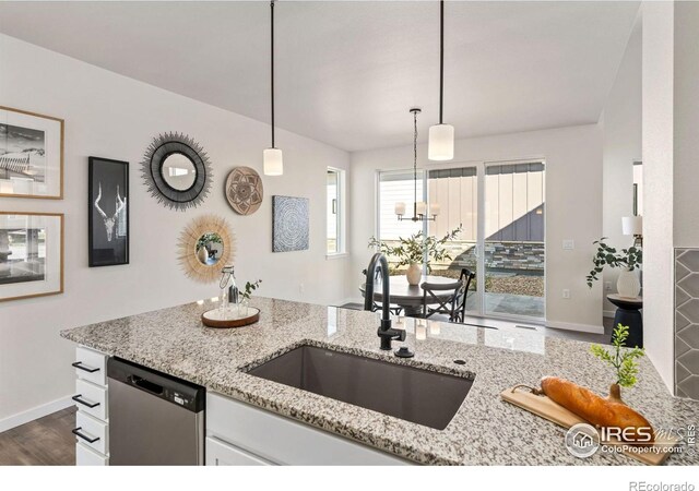 kitchen with a sink, dark wood finished floors, white cabinetry, light stone countertops, and dishwasher