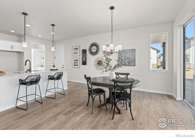 dining space with recessed lighting, light wood finished floors, baseboards, and a notable chandelier