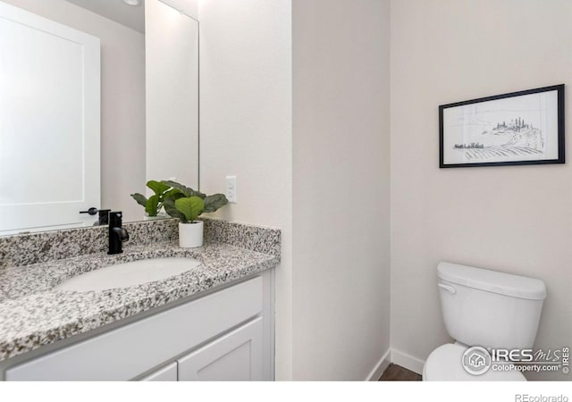 bathroom featuring toilet, vanity, and baseboards