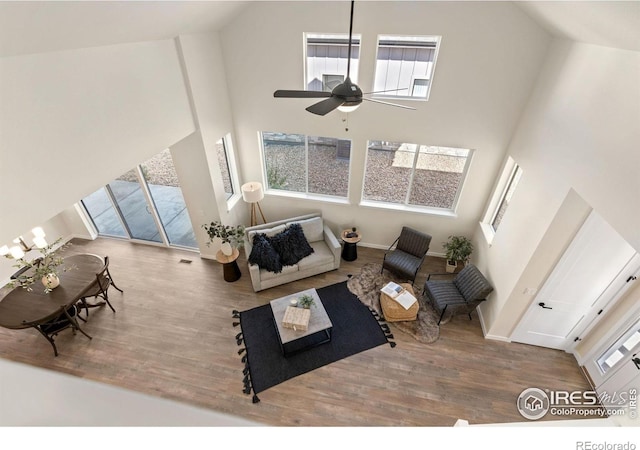 living room with wood finished floors, a high ceiling, a ceiling fan, and baseboards