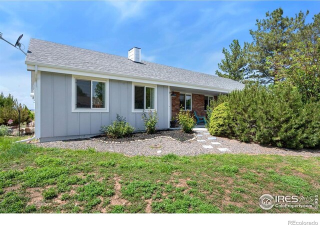 7859 Whitetail Cir, Wellington, CO 80549 - ranch-style home with board and batten siding, a chimney, a front yard, and a shingled roof