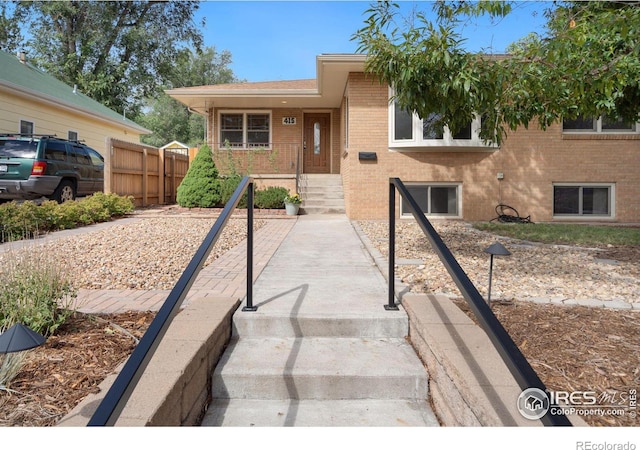 view of front of home featuring brick siding and fence