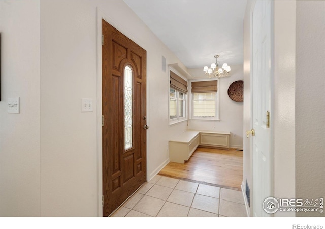 entrance foyer featuring a notable chandelier, baseboards, light tile patterned flooring, and visible vents