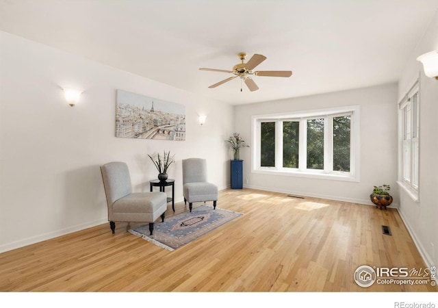 sitting room with visible vents, baseboards, wood finished floors, and ceiling fan
