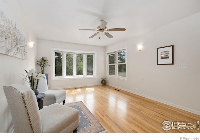 sitting room with wood finished floors, a ceiling fan, and baseboards