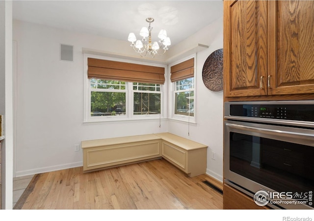kitchen featuring light wood-style flooring, stainless steel oven, visible vents, an inviting chandelier, and pendant lighting