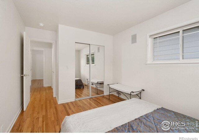 bedroom featuring baseboards, visible vents, light wood finished floors, and a closet