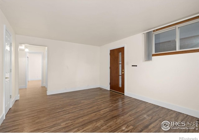 spare room with dark wood finished floors and baseboards