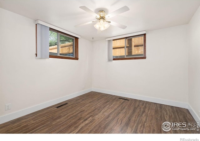 unfurnished room with baseboards, a ceiling fan, visible vents, and dark wood-style flooring