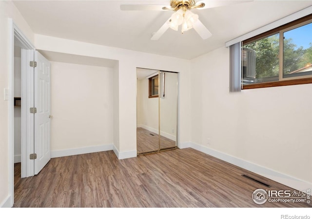 unfurnished bedroom featuring baseboards, wood finished floors, visible vents, and a closet