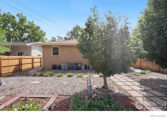 rear view of house featuring a fenced backyard, brick siding, and cooling unit