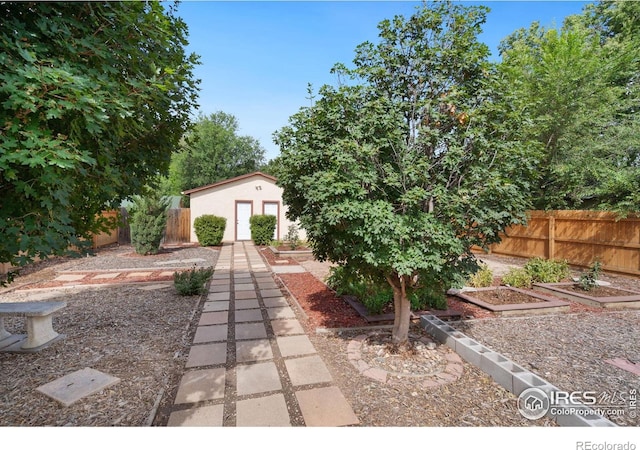 view of yard featuring fence, a garden, and an outbuilding