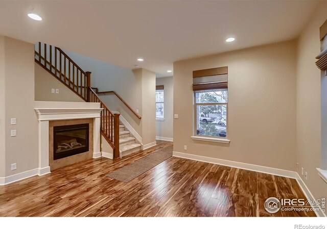 8482 Parkland St, Broomfield, CO 80021 - unfurnished living room featuring stairway, wood finished floors, recessed lighting, baseboards, and a tile fireplace