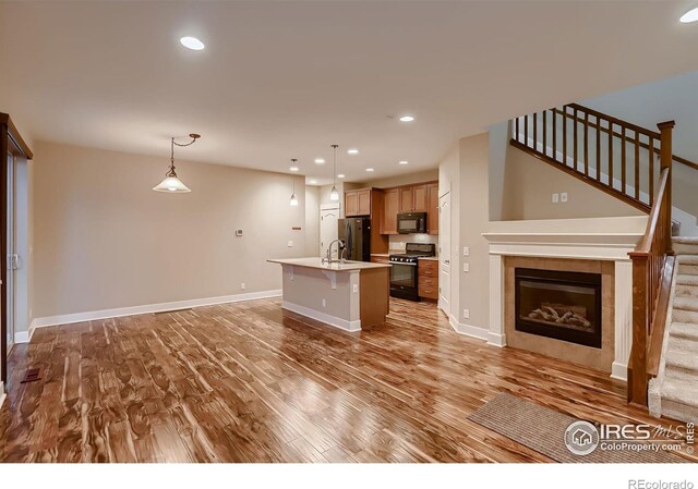8482 Parkland St, Broomfield, CO 80021 - kitchen featuring black appliances, open floor plan, light wood finished floors, a breakfast bar area, and a sink