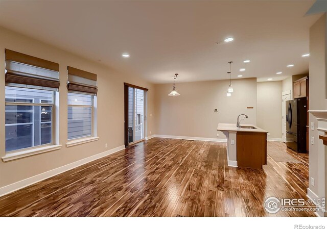 8482 Parkland St, Broomfield, CO 80021 - kitchen with freestanding refrigerator, a sink, dark wood-style floors, a kitchen island with sink, and pendant lighting