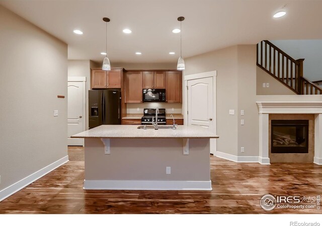 8482 Parkland St, Broomfield, CO 80021 - kitchen with black appliances, an island with sink, dark wood-style floors, a kitchen bar, and recessed lighting