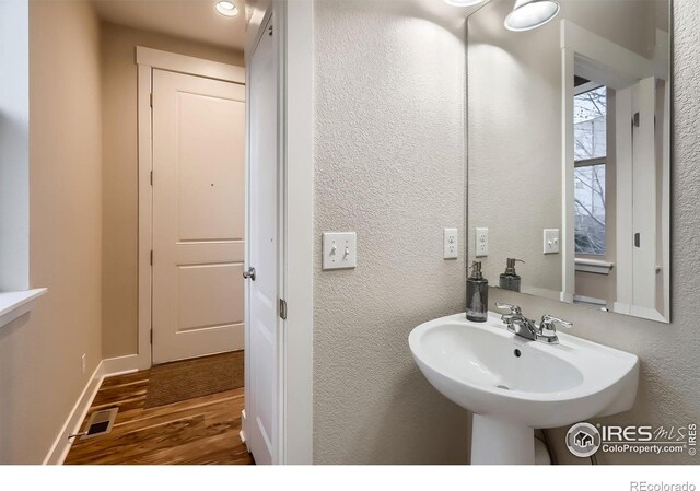 8482 Parkland St, Broomfield, CO 80021 - bathroom with wood finished floors, a sink, a textured wall, and baseboards