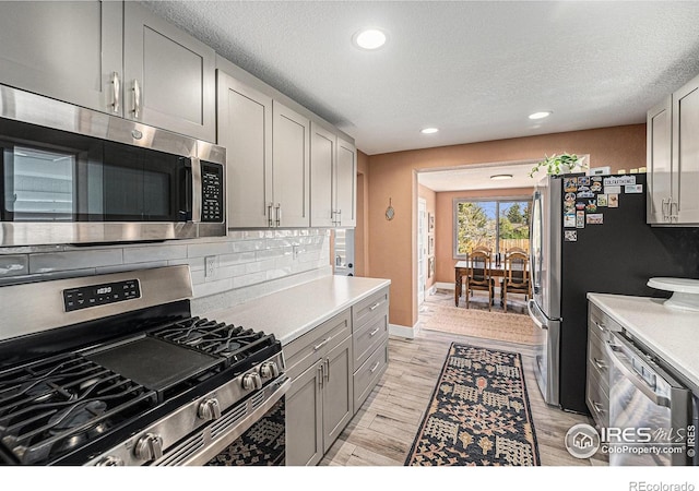 2566 S Stuart St, Denver, CO 80219 - kitchen featuring stainless steel appliances, gray cabinets, recessed lighting, light countertops, and decorative backsplash