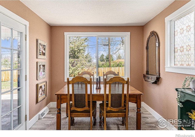 2566 S Stuart St, Denver, CO 80219 - dining space with a textured wall, light wood-type flooring, and baseboards
