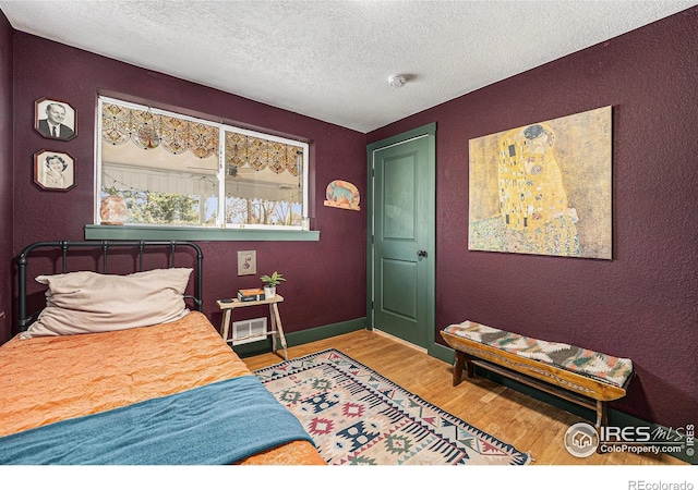 2566 S Stuart St, Denver, CO 80219 - bedroom featuring wood finished floors, a textured ceiling, a textured wall, and baseboards