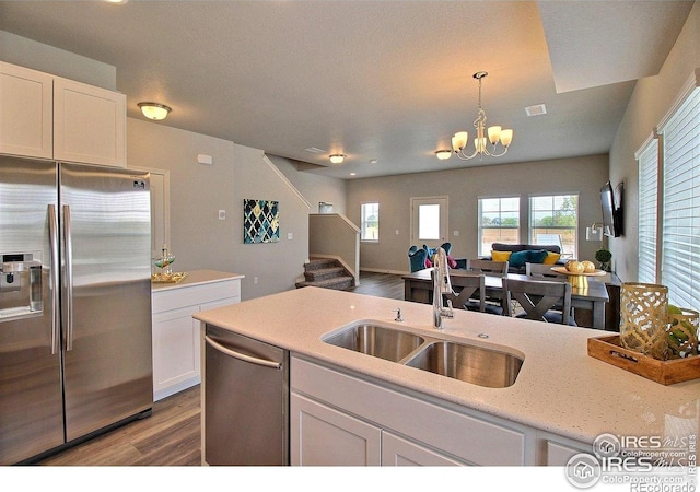 1693 Grand Ave Unit 1, Windsor, CO 80550 - kitchen featuring stainless steel appliances, a sink, open floor plan, wood finished floors, and white cabinetry