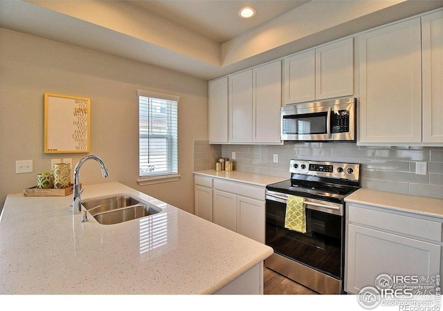 1693 Grand Ave Unit 1, Windsor, CO 80550 - kitchen with stainless steel appliances, a sink, recessed lighting, tasteful backsplash, and white cabinets
