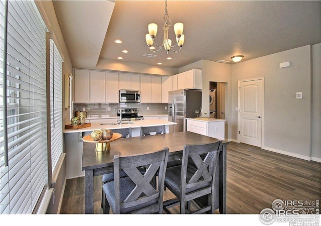 1693 Grand Ave Unit 1, Windsor, CO 80550 - kitchen featuring appliances with stainless steel finishes, a sink, stacked washer / drying machine, light countertops, and a chandelier