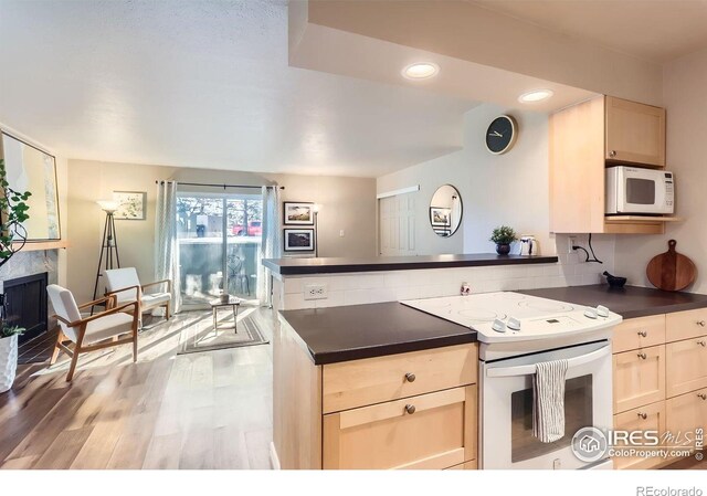 695 Manhattan Dr Unit 22, Boulder, CO 80303 - kitchen featuring a peninsula, light wood-type flooring, dark countertops, white appliances, and a fireplace