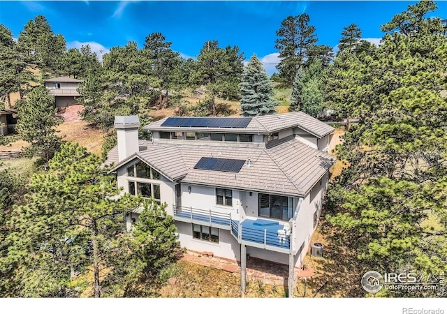 36 High View Dr, Boulder, CO 80304 - back of house with solar panels, stucco siding, a balcony, a chimney, and a tiled roof