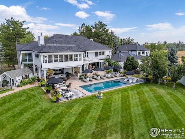 back of house with a patio area, a balcony, a yard, and an outdoor pool