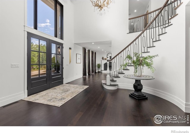 entrance foyer featuring a towering ceiling, wood finished floors, baseboards, french doors, and stairway