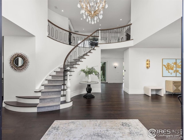 foyer entrance featuring wood finished floors, stairs, a towering ceiling, a chandelier, and recessed lighting
