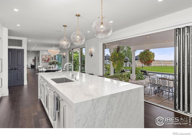 kitchen with a sink, recessed lighting, white cabinetry, dark wood-type flooring, and light stone countertops