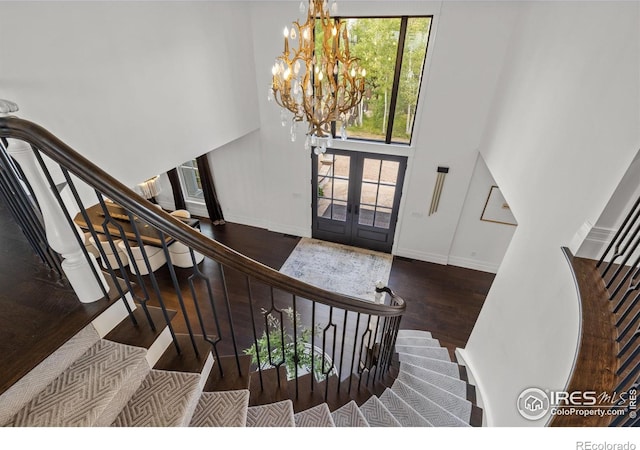 entryway featuring stairs, wood finished floors, french doors, a high ceiling, and a chandelier