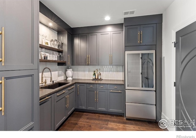 kitchen featuring a sink, refrigerator, dark wood-style flooring, decorative backsplash, and open shelves