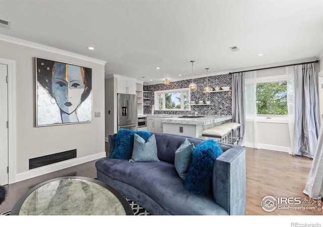living room featuring baseboards, wood finished floors, crown molding, and recessed lighting