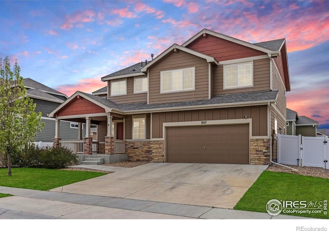 craftsman house with board and batten siding, a porch, a gate, and stone siding