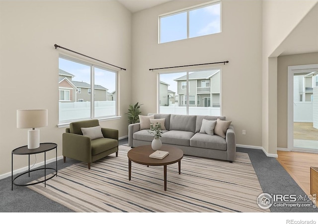 living area featuring baseboards, a high ceiling, and carpet