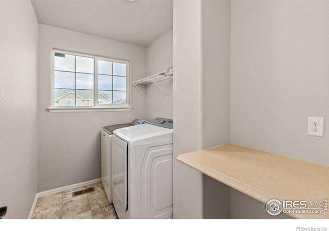 clothes washing area with independent washer and dryer, laundry area, visible vents, and baseboards