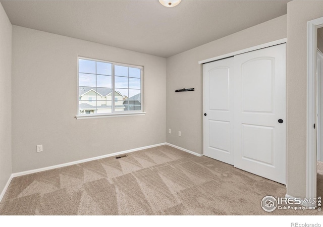 unfurnished bedroom featuring visible vents, carpet, baseboards, and a closet