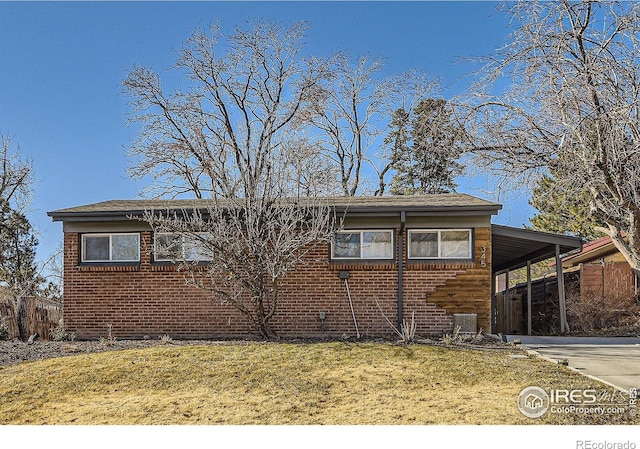 ranch-style house featuring brick siding, fence, a front lawn, concrete driveway, and an attached carport