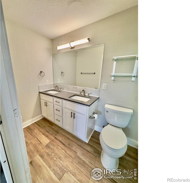 full bath featuring double vanity, toilet, a sink, and wood finished floors