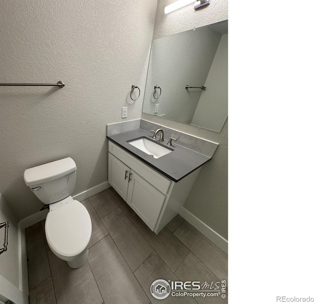 bathroom with vanity, a textured wall, and toilet