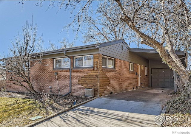 view of side of property with a garage, cooling unit, brick siding, concrete driveway, and a carport