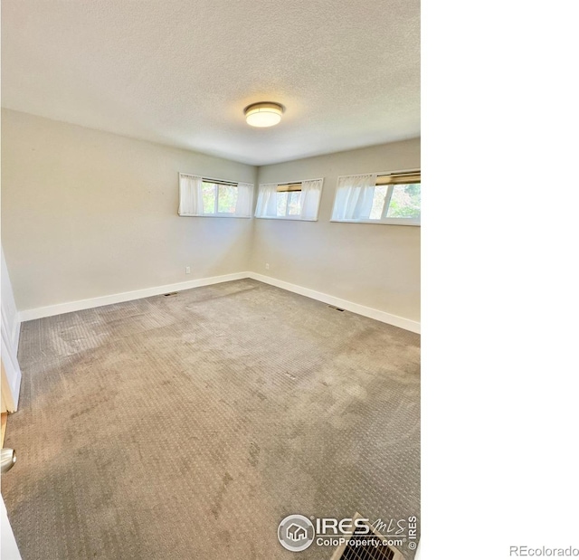 empty room featuring baseboards, carpet flooring, and a textured ceiling