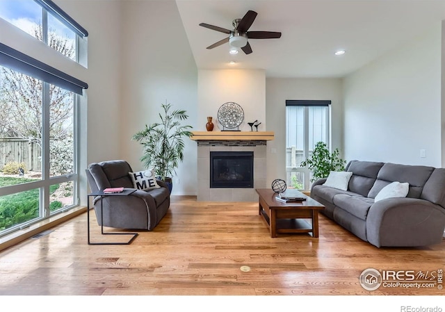 living area featuring a tile fireplace, wood finished floors, and a healthy amount of sunlight