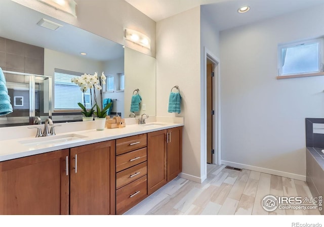bathroom with recessed lighting, a sink, a shower stall, and double vanity